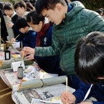 竹灯籠に筆で文字を書き込む中学生たち＝神戸市北区山田町