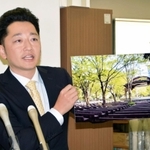 「１・１７のつどい」東京会場の詳細について、日比谷公園の写真パネルを示しながら話す藤本真一委員長＝１８日午前、神戸市役所
