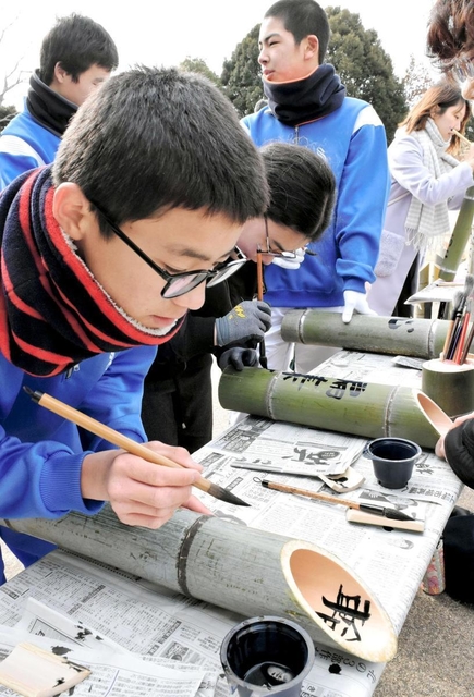 竹灯籠に思い思いの文字を書き入れる中学生ら＝神戸市北区山田町藍那