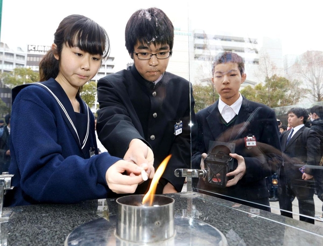 「１・１７希望の灯り」からろうそくに火を移す生徒たち＝１２日午後、神戸市中央区加納町６、東遊園地（撮影・辰巳直之）