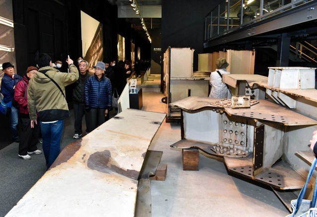 震災で損壊した部材の前で説明を聞く来館者ら＝神戸市東灘区深江浜町