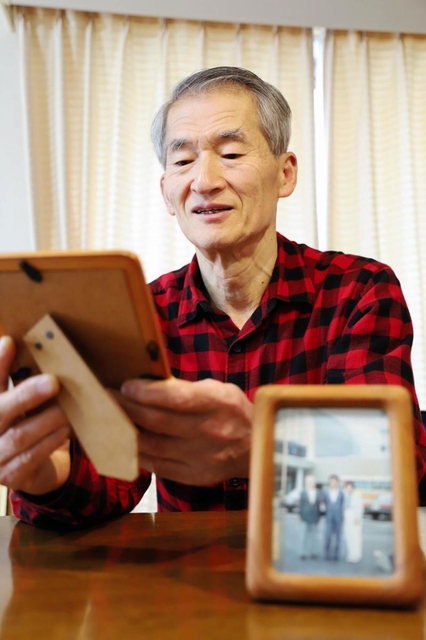 実家は全焼し、手元に残った両親の写真を見つめる野田栄司さん＝西宮市