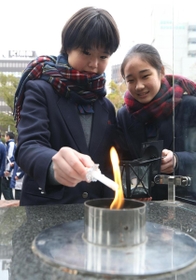 「１・１７希望の灯り」からろうそくに火を移す生徒たち＝１２日午後、神戸市中央区加納町６、東遊園地（撮影・辰巳直之）