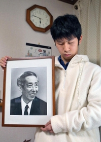 「この時間は寒いし暗い。おじいちゃんもそう感じたかな」。阪神・淡路大震災で亡くなった祖父幸田修一さんの遺影を抱く行武峻さん＝１７日午前５時４６分、西宮市（撮影・風斗雅博）