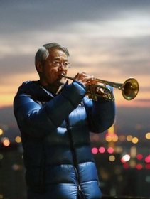 朝焼けを背に、最後となるトランペットを奏でる松平晃さん＝１７日午前６時３７分、神戸市中央区神戸港地方、ビーナスブリッジ（撮影・吉田敦史）