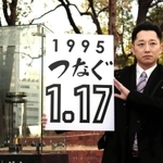 「１・１７のつどい」で描く文字を掲げる藤本真一実行委員長＝１１日午後、神戸市中央区、東遊園地