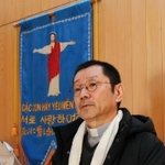 「顔見知りの関係をつくることが大切」と語る神田裕さん。聖堂の壁には、ベトナム、ハングル、日本語で表記されたタペストリーがある＝カトリックたかとり教会