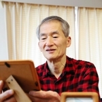 実家は全焼し、手元に残った両親の写真を見つめる野田栄司さん＝西宮市