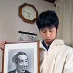 「この時間は寒いし暗い。おじいちゃんもそう感じたかな」。阪神・淡路大震災で亡くなった祖父幸田修一さんの遺影を抱く行武峻さん＝１７日午前５時４６分、西宮市（撮影・風斗雅博）