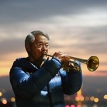 朝焼けを背に、最後となるトランペットを奏でる松平晃さん＝１７日午前６時３７分、神戸市中央区神戸港地方、ビーナスブリッジ（撮影・吉田敦史）