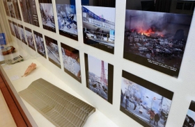 震災直後の神戸を撮影した写真パネルや、地震でゆがんだ側溝のふたなどが展示されている＝神戸市中央区下山手通４