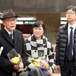 弟今村幸司さんの銘板が追加された思いを語る（左から）今村憲司さん、妻佐智子さん、長男治樹さん＝１４日午後、神戸市中央区加納町６、東遊園地（撮影・吉田敦史）