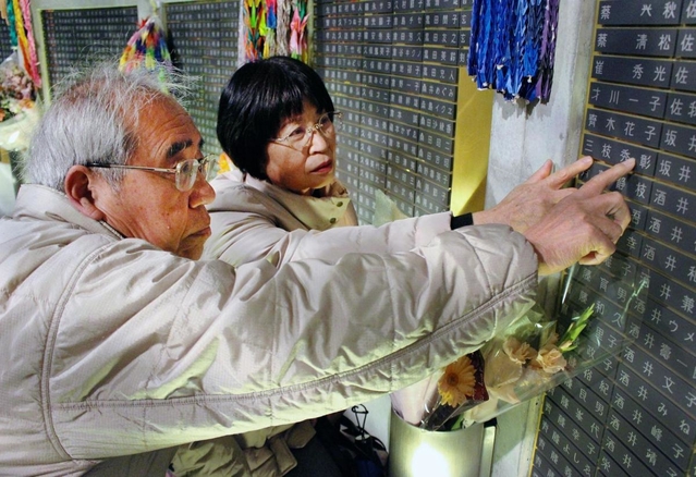 亡くなった長男秀彰さんの銘板を確認する三枝さん夫妻＝１８日午前５時２４分、神戸市中央区、東遊園地