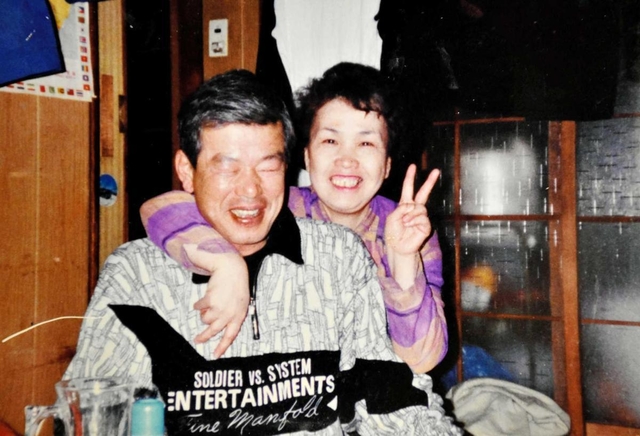 照れながら妻の久代さんと写真に納まる加久幾康さん（左）