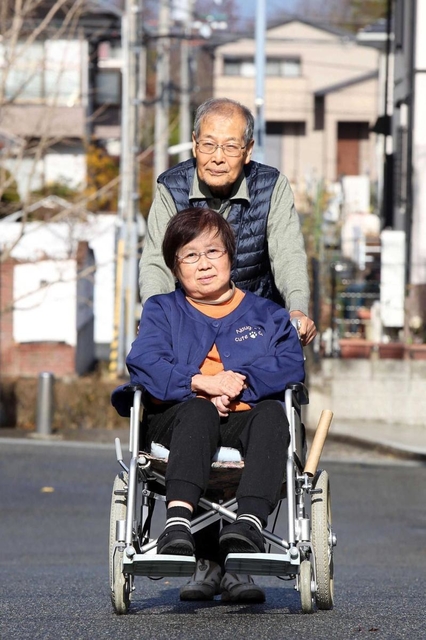 夫の雅男さんに押してもらいながら、車いすで近所を散歩する村田延子さん＝神戸市北区鹿の子台（撮影・風斗雅博）