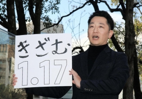 「１・１７のつどい」で描く文字を掲げる藤本真一実行委員長＝１０日午後、神戸市中央区加納町６、東遊園地