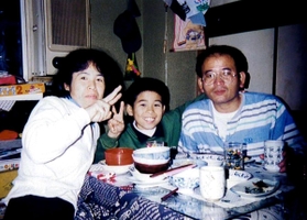 自宅でくつろぐ高田隼渡さん（中央）と父義文さん（右）、母キクヨさん＝神戸市中央区（１９９４年、隼渡さん提供））