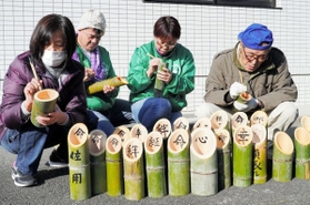 阪神・淡路大震災の追悼行事に並べる竹灯籠に、文字を書き入れる人々＝佐用町下徳久