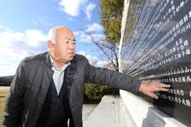 震災で亡くなった父国夫さんの名前を触る山本国輝さん＝西宮市奥畑、西宮震災記念碑公園（撮影・風斗雅博）