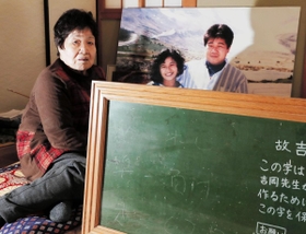 阪神・淡路大震災で長男の吉岡真治さんと千恵美さん夫妻を亡くした吉岡君江さん。大きく引き延ばした写真と真治さんの文字が残る黒板が心の支えだ＝神戸市北区大池見山台