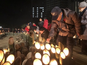阪神・淡路大震災から丸２５年を迎えた朝、竹灯籠のろうそくに火をともす人たち＝１７日午前５時２２分、神戸市中央区の東遊園地
