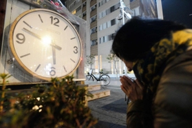地震発生時刻で停止した時計のモニュメントに手を合わせる女性＝１７日午前６時３分、西宮市田中町（撮影・三津山朋彦）西宮中央商店街