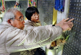 亡くなった長男秀彰さんの銘板を確認する三枝さん夫妻＝１８日午前５時２４分、神戸市中央区、東遊園地
