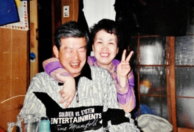 照れながら妻の久代さんと写真に納まる加久幾康さん（左）