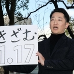 「１・１７のつどい」で描く文字を掲げる藤本真一実行委員長＝１０日午後、神戸市中央区加納町６、東遊園地