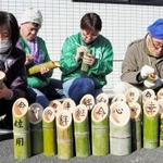 阪神・淡路大震災の追悼行事に並べる竹灯籠に、文字を書き入れる人々＝佐用町下徳久