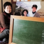 阪神・淡路大震災で長男の吉岡真治さんと千恵美さん夫妻を亡くした吉岡君江さん。大きく引き延ばした写真と真治さんの文字が残る黒板が心の支えだ＝神戸市北区大池見山台