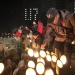 阪神・淡路大震災から丸２５年を迎えた朝、竹灯籠のろうそくに火をともす人たち＝１７日午前５時２２分、神戸市中央区の東遊園地