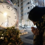 地震発生時刻で停止した時計のモニュメントに手を合わせる女性＝１７日午前６時３分、西宮市田中町（撮影・三津山朋彦）西宮中央商店街