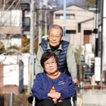 夫の雅男さんに押してもらいながら、車いすで近所を散歩する村田延子さん＝神戸市北区鹿の子台（撮影・風斗雅博）