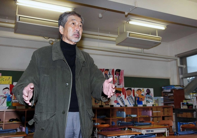 阪神・淡路大震災の発生後、ＰＴＡ会長として避難所運営を担った神戸市議の浦上忠文さん。着用していたジャンパーを羽織り、当時を振り返る＝神戸市東灘区御影山手１、御影北小学校