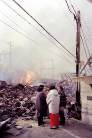 不安そうな表情で話し込む住民。その向こうに延焼する火が見える＝１９９５年１月１７日午前、神戸市灘区新在家北町２