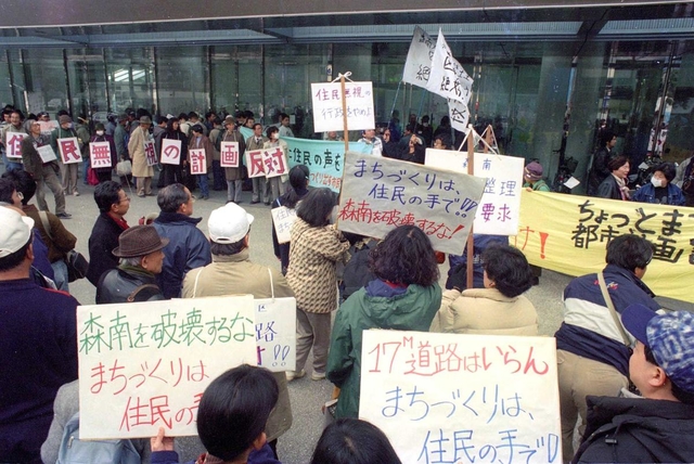 神戸市都市計画審議会が開かれる市役所前でプラカードや横断幕を掲げ、市の復興まちづくり案に抗議する市民ら＝１９９５年３月１４日