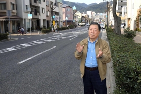 土地区画整理で道路が拡幅された「川東線」で、震災時の様子を語る康本邦三さん＝芦屋市大桝町