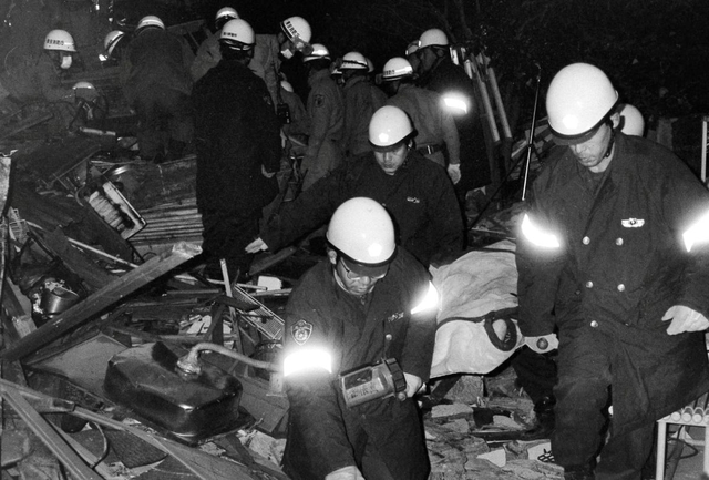 倒壊したマンションから運び出される住民＝１９日夜、芦屋市打出町