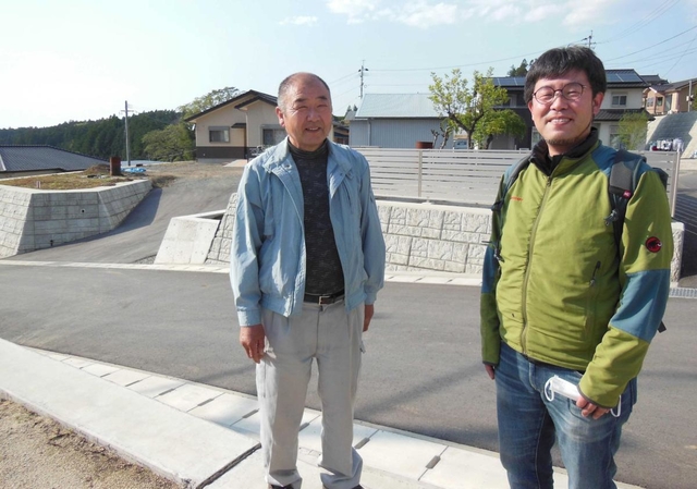 擁壁整備や道路拡幅など復旧事業の完了を喜ぶ元区長の坂田哲也さん（左）。佐々木康彦さんは新潟県中越地震の教訓を伝え、復興を支えた＝熊本県西原村
