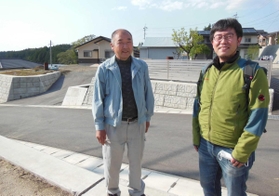 擁壁整備や道路拡幅など復旧事業の完了を喜ぶ元区長の坂田哲也さん（左）。佐々木康彦さんは新潟県中越地震の教訓を伝え、復興を支えた＝熊本県西原村