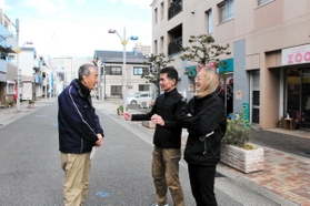 街の再出発から２０年がたつ鷹取商店街で話をする小林延行さん（中央）ら＝神戸市長田区若松町１１