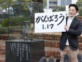 「１・１７のつどい」で描かれる文字を掲げる藤本真一実行委員長＝１２日午後、神戸市中央区の東遊園地（撮影・大森　武）