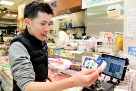 キャッシュレス決済ができるカードを端末にかざすセルバ名店会の北野良征さん＝神戸市東灘区森南町１