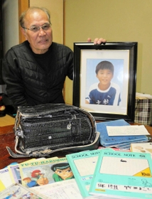 誠さんの遺影を持つ守さん。ランドセルや教科書、ノートは大切な宝物だ＝西宮市越水町