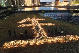 ライトアップされ、夕闇に浮かび上がる石積みの「生」の文字＝１６日午後５時４６分、宝塚市の武庫川（撮影・斎藤雅志）