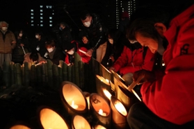 竹灯籠に火をともす人たち＝１７日午前４時４８分、神戸市中央区加納町６（撮影・大森　武）