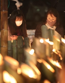 竹灯籠に火をともす女性ら＝１７日午前４時５３分、神戸市中央区加納町６、東遊園地（撮影・辰巳直之）