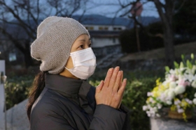 兄・顕さんの名前が刻まれた記念碑に手を合わせる北佐和子さん＝１７日午前６時５８分、西宮市奥畑
