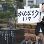 「１・１７のつどい」で描かれる文字を掲げる藤本真一実行委員長＝１２日午後、神戸市中央区の東遊園地（撮影・大森　武）